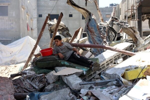 Un menor palestino descansa sobre los escombros de un edificio cerca de un centro de distribución de alimentos en Jabaliya. 