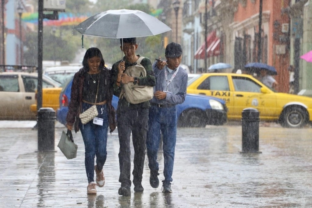 Personas se protegen de las lluvias provocadas por la tormenta tropical 'Nadine'.