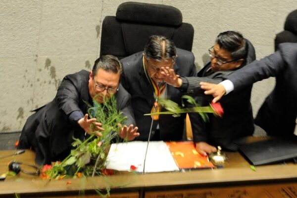 El vicepresidente de Bolivia, David Choquehuanca, se protege de objetos que simpatizantes de Morales arrojaron en la Asamblea Plurinacional. 