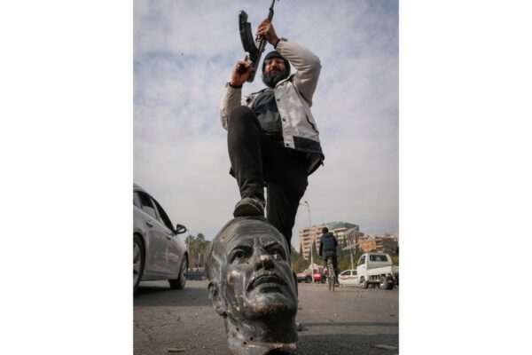 Combatiente celebra en Damasco sobre los restos de una estatua de Hafez al Assad, padre del derrocado presidente sirio Bashar al Assad.