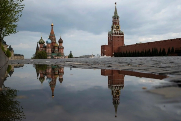 La Torre Spasskaya del Kremlin, al centro, y la Catedral de San Basilio reflejadas en el agua de lluvia en la Plaza Roja de Moscú.