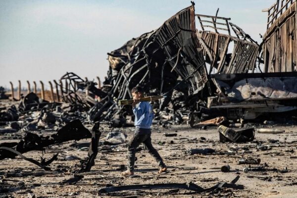 Un menor encontró una granada propulsada por cohetes en medio de la devastación de una zona bombardeada por Israel en Qamishli, Siria.