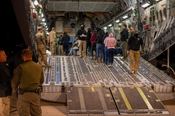 Esta imagen del Departamento de Defensa muestra a aviadores estadunidenses y agentes de Aduanas y Protección Fronteriza, mientras guían a migrantes indocumentados dentro de un C-17 Globemaster III de uso militar en el aeropuerto de Tucson, Arizona.