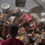 En el campo de refugiados de Jan Yunis, palestinos disputan alimentos en una cocina comunitaria.