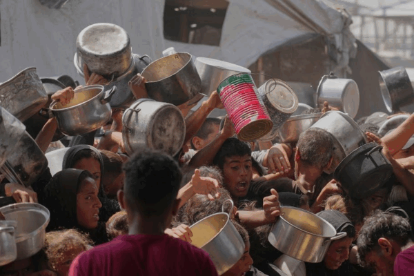 En el campo de refugiados de Jan Yunis, palestinos disputan alimentos en una cocina comunitaria.