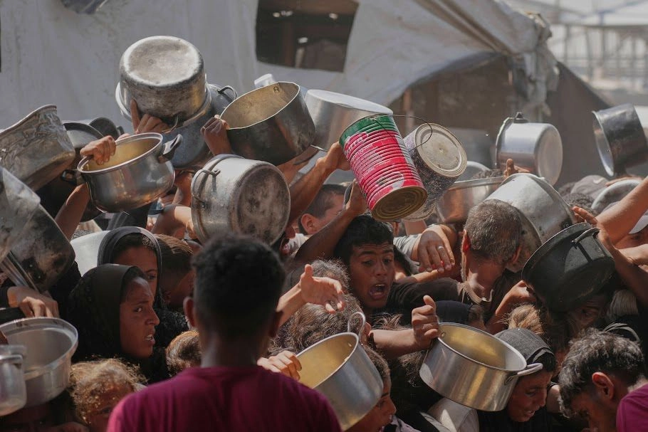 En el campo de refugiados de Jan Yunis, palestinos disputan alimentos en una cocina comunitaria.