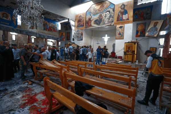 Sirios se reúnen dentro de la iglesia de Mar Elias, donde un atacante suicida se detonó en Dweil'a, en las afueras de Damasco, Siria.