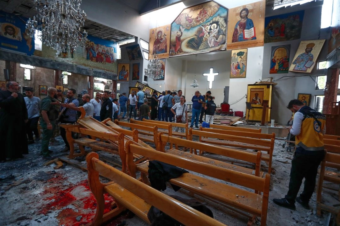 Sirios se reúnen dentro de la iglesia de Mar Elias, donde un atacante suicida se detonó en Dweil'a, en las afueras de Damasco, Siria.