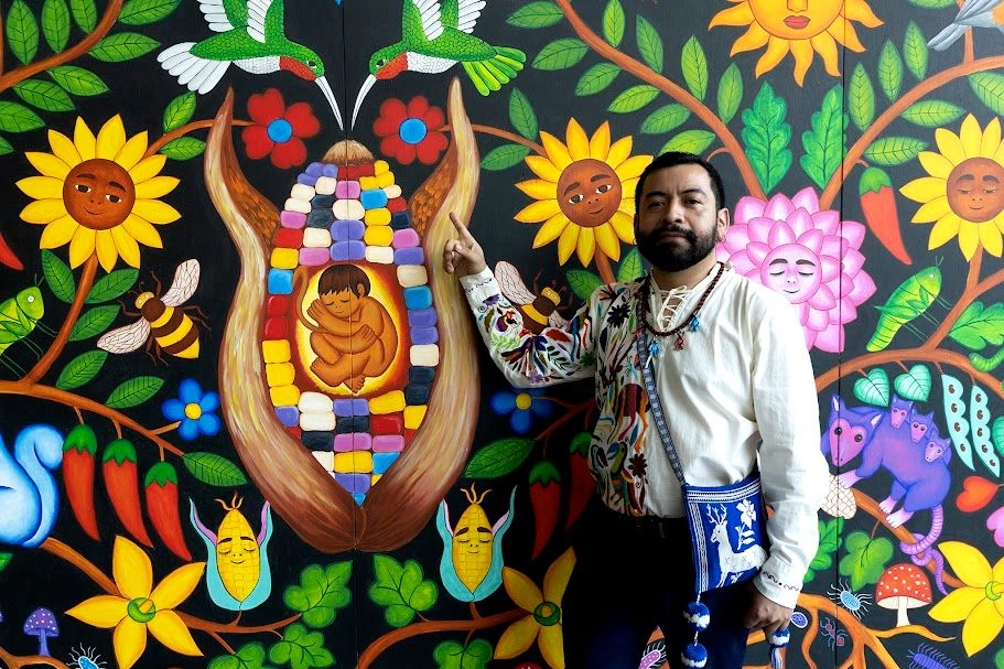 En los lienzos de Santiago Savi hay semillas. Algunas germinan en forma de elotes con ojos y sonrisa, otras florecen como flores que hablan, serpientes que flotan sobre campos arados, jaguares que velan el sueño de la tierra o abuelas de humo que caminan entre los surcos.