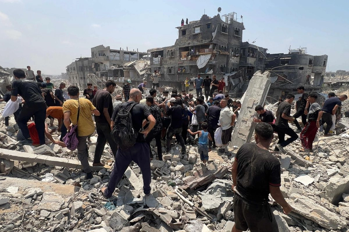 Palestinos se arremolinan sobre un paquete humanitario lanzado por un avión militar en Jabalia, en el norte de la franja de Gaza, el 9 de agosto de 2025.