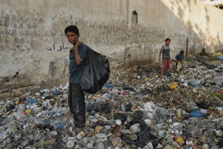 Yassin al Masry, de 13 años, recolecta plástico entre la basura para hacer fuego con el cual cocinar, en la ciudad de Gaza.