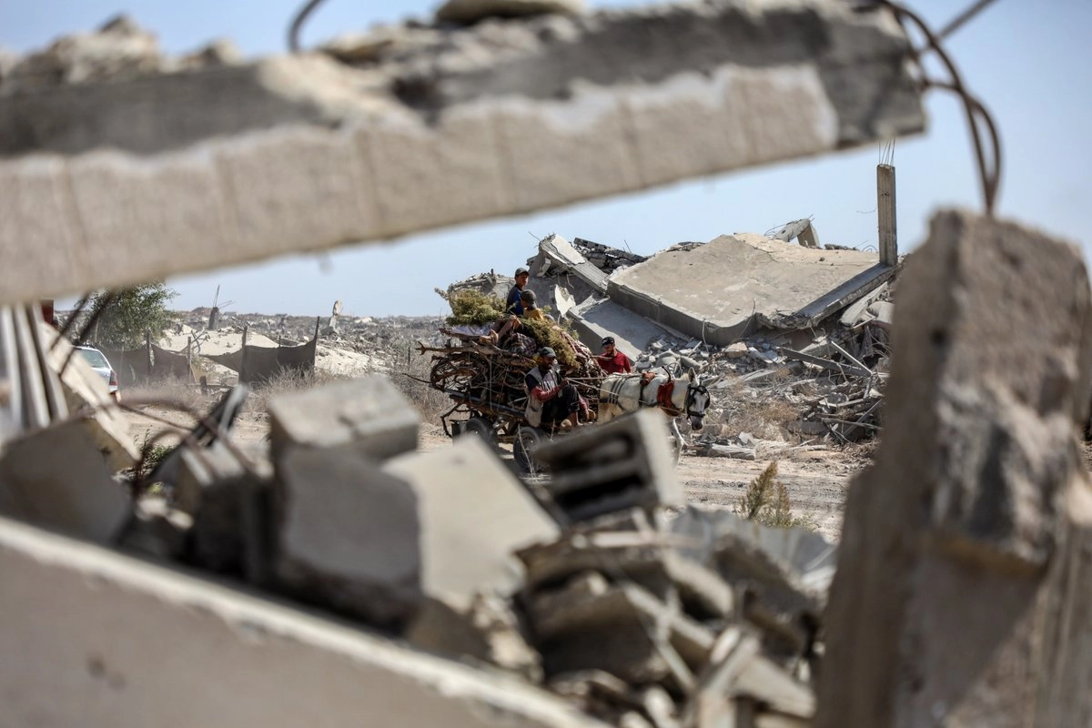Imagen del 11 de octubre de 2025 de palestinos cargando sus pertenencias a su regreso al norte a lo largo de la carretera Salah al-Din, en el centro de la Franja de Gaza.