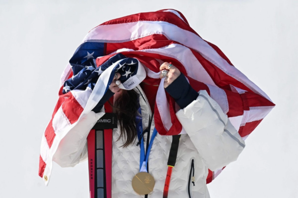 La medallista de oro estadunidense Breezy Johnson posa con la bandera de EU en el podio del evento de descenso femenino durante los Juegos Olímpicos de Invierno Milano Cortina 2026 en el Centro de Esquí Alpino Tofane en Cortina d'Ampezzo.