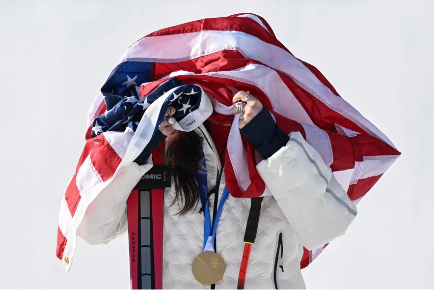 La medallista de oro estadunidense Breezy Johnson posa con la bandera de EU en el podio del evento de descenso femenino durante los Juegos Olímpicos de Invierno Milano Cortina 2026 en el Centro de Esquí Alpino Tofane en Cortina d'Ampezzo.