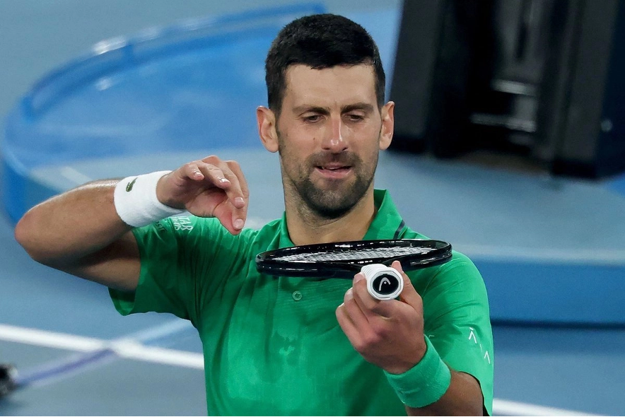 El serbio Novak Djokovic simula tocar el violín con la raqueta mientras celebra su victoria en el Abierto de Australia.