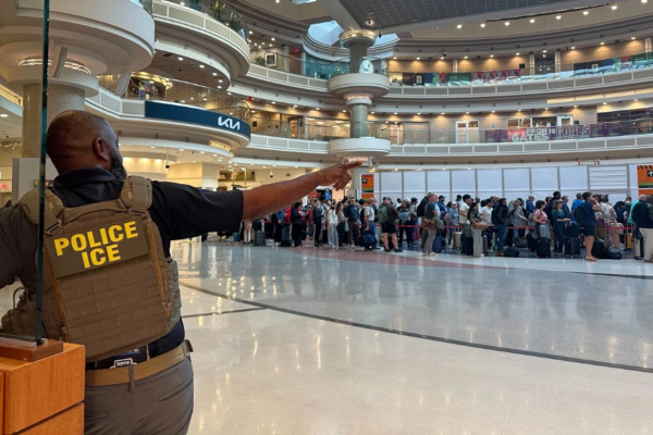 Un agente federal de inmigración observa a personas haciendo fila en el control de seguridad del aeropuerto internacional Hartsfield-Jackson de Atlanta, el lunes 23 de marzo de 2026.