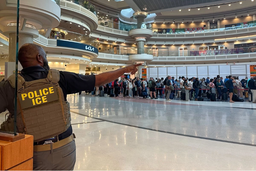 Un agente federal de inmigración observa a personas haciendo fila en el control de seguridad del aeropuerto internacional Hartsfield-Jackson de Atlanta, el lunes 23 de marzo de 2026.