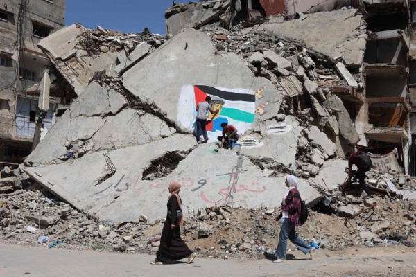 Dos jóvenes pintan el rostro de Lamine Yamal sobre unas ruinas en Gaza.