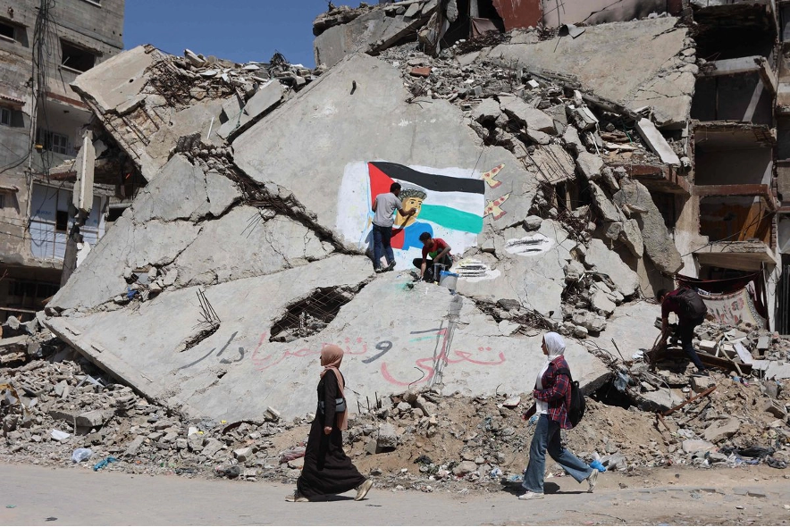 Dos jóvenes pintan el rostro de Lamine Yamal sobre unas ruinas en Gaza.