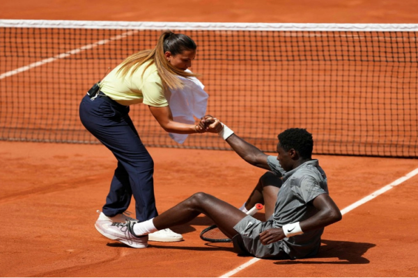 La jueza de silla brasileña Ana Carvalho ayuda al francés Moise Kouame a levantarse tras caerse a la pista mientras jugaba contra el paraguayo Adolfo Daniel Vallejo durante su partido individual masculino en la quinta jornada del torneo de tenis Roland Garros, en la pista Suzanne-Lenglen del complejo Roland-Garros de París.