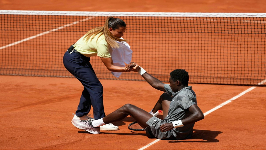 La jueza de silla brasileña Ana Carvalho ayuda al francés Moise Kouame a levantarse tras caerse a la pista mientras jugaba contra el paraguayo Adolfo Daniel Vallejo durante su partido individual masculino en la quinta jornada del torneo de tenis Roland Garros, en la pista Suzanne-Lenglen del complejo Roland-Garros de París.