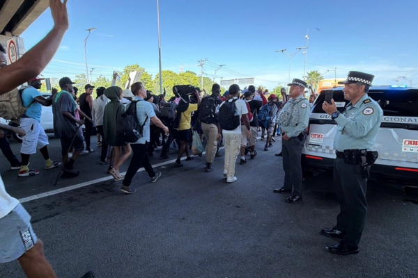 La caravana "De la mano de Dios" es conformada por unos 200 migrantes, en su mayoría originarios de Cuba, Venezuela, Haití, Ecuador, Honduras y El Salvador; en la imagen, el contingente es visto pasar por elementos de la Guardia Nacional en Chiapas. 