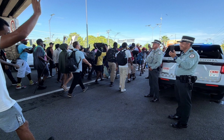 La caravana "De la mano de Dios" es conformada por unos 200 migrantes, en su mayoría originarios de Cuba, Venezuela, Haití, Ecuador, Honduras y El Salvador; en la imagen, el contingente es visto pasar por elementos de la Guardia Nacional en Chiapas. 