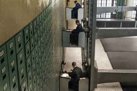 La fotografía parece de una película de ciencia ficción: tres funcionarios aparecen sentados en una especie de cabinas que son una extraña mezcla de ascensor y escritorio de trabajo.