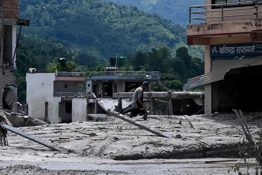 Un hombre recupera pertenencias de su casa, anegada por el lodo tras unas inundaciones repentinas en la zona de Devighat, en el distrito nepalí de Nuwakot, el 27 de agosto de 2026.